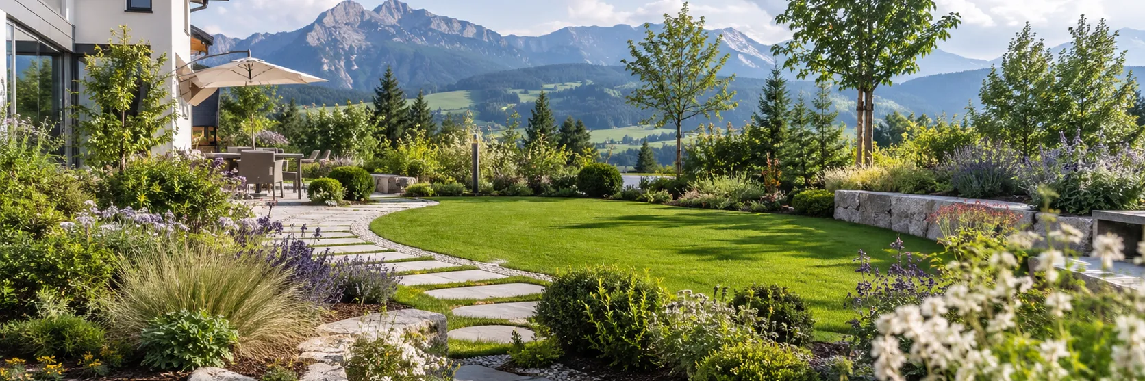 Neu gestalteter Garten mit Natursteinweg, Staudenbeeten und Rasenfläche vor modernem Haus mit Allgäuer Bergpanorama